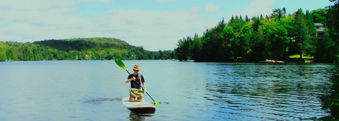 Youth on lake riding stand up paddle board