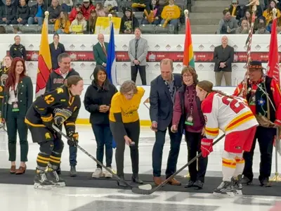 Councillor and other officials dropping puck at hockey game.