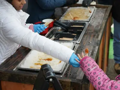 child reaching out to maple syrup on snow