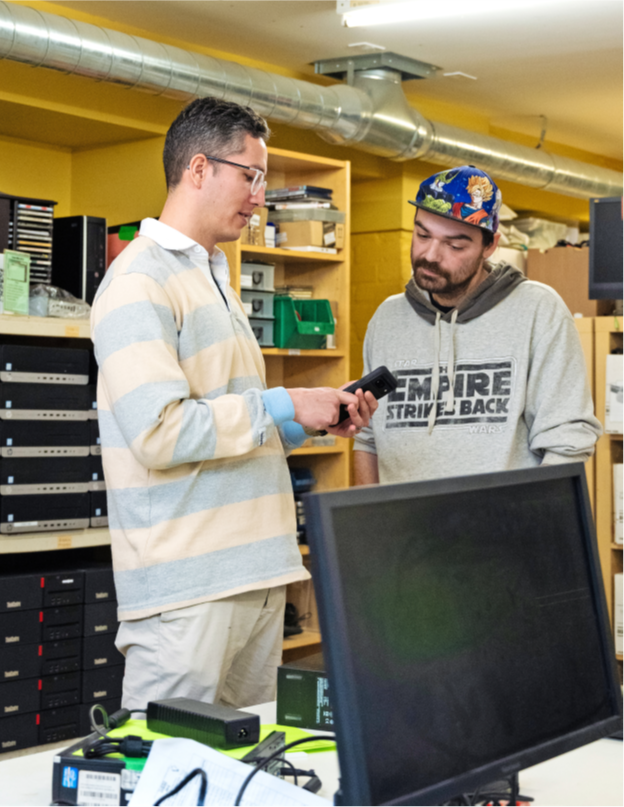 Two men in an IT office looking at a phone and talking 