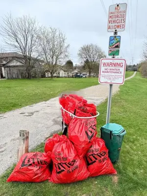 Garbage bags sitting next to a City of Kitchener trail