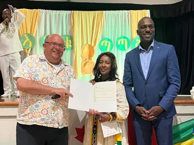 Two men and a women standing with a certificate