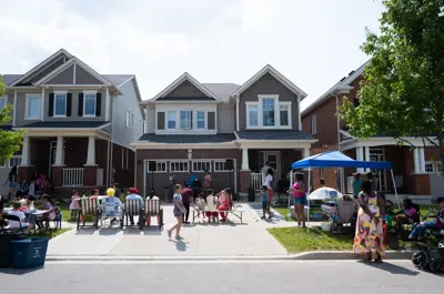 Group of people sitting in chairs in driveway watching musicians perform