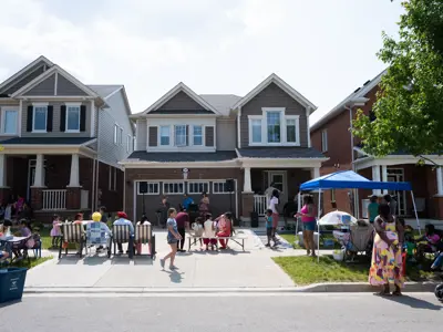 Group of people sitting in chairs in driveway watching musicians perform