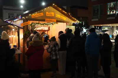 Patrons waiting for an item at an outdoor hut during Christkindl Market