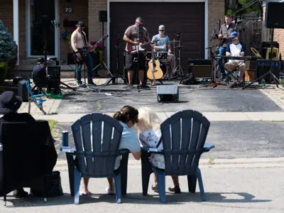 kids sitting on chairs watching musician perform on front porch