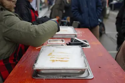 Person pouring maple syrup on snow to make maple syrup taffy