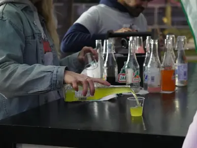 person pouring drinks into a cup at the bar