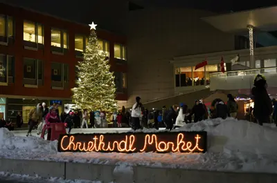 Christkindl Market sign with individuals skating on a rink in the background