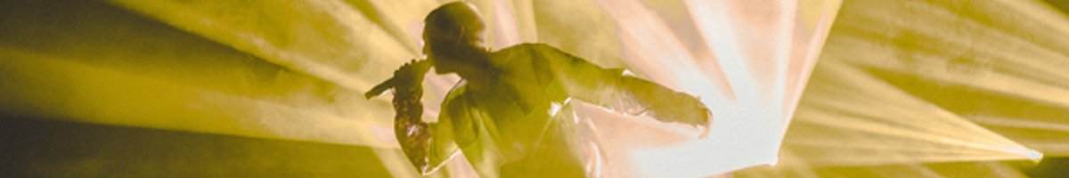 Person singing on stage with yellow lights around them