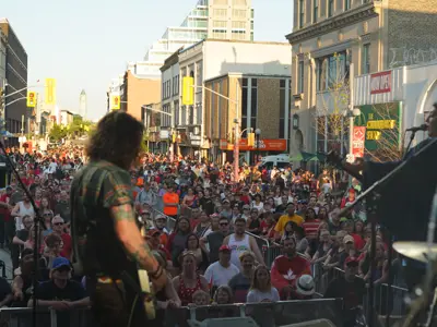 man playing guitar with crowd in background at outside concert