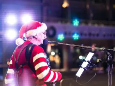 Man in a Santa hat playing accordion on a stage
