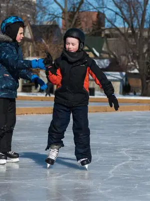 two kids skating on an outdoor rink