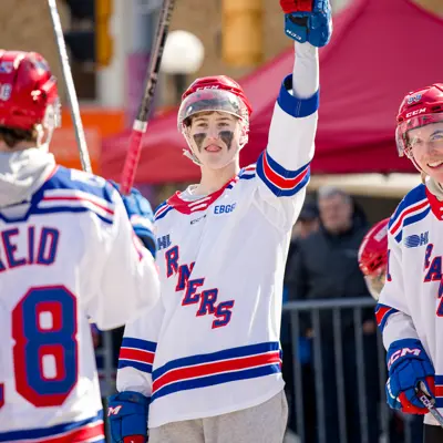 Kitchener Rangers player lifting his stick in the air in victory after scoring a goal