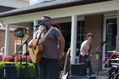 man with acoustic guitar performing in front of crowd outside