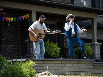 two men with acoustic guitars performing on a porch