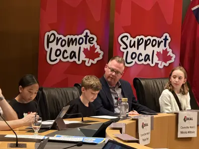 Councillor sitting in council chambers with group of youth
