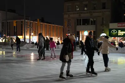 Patrons skating on the ice rink outside of City Hall