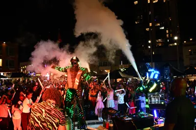 Performers lit up by neon lights on an outdoor stage at night