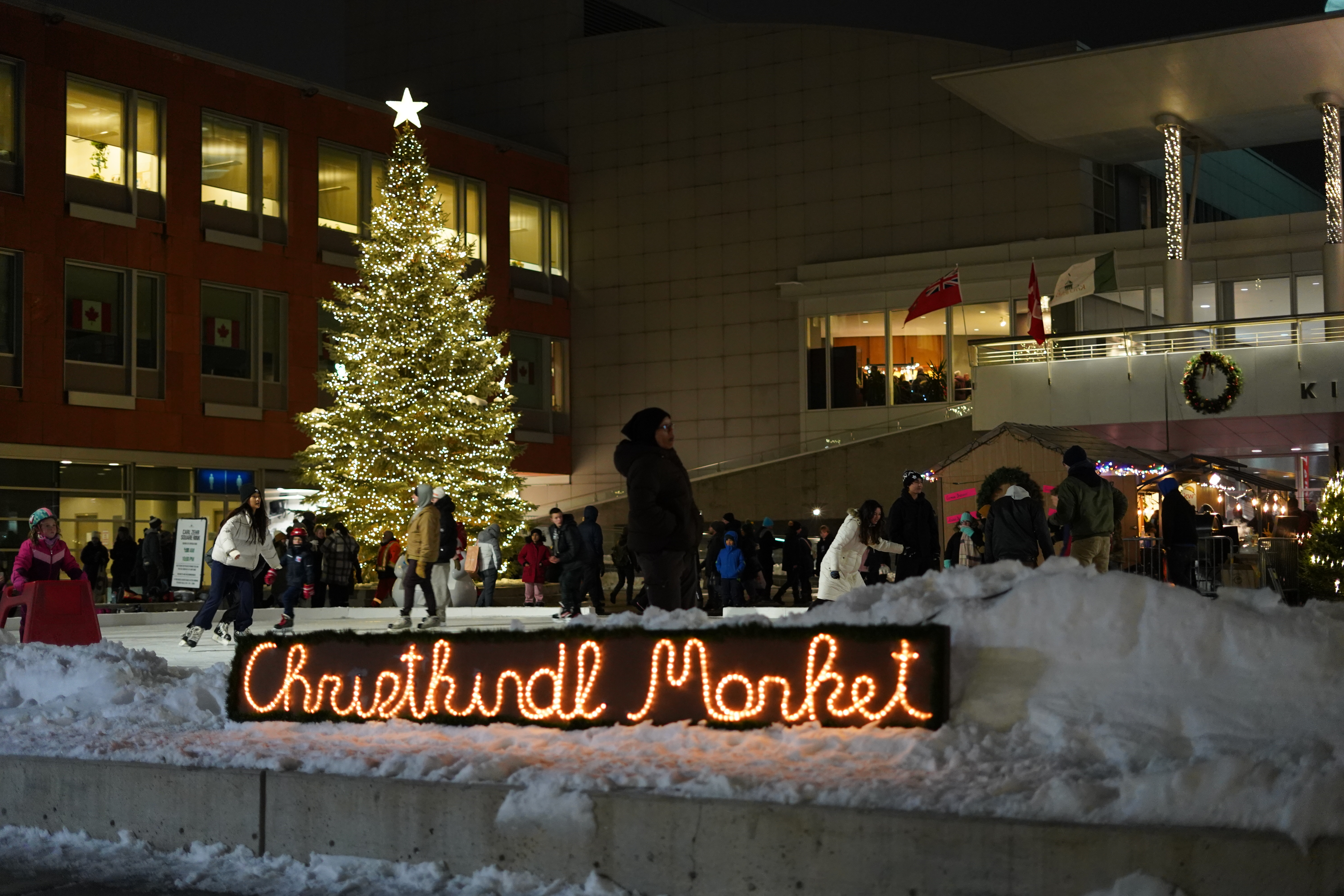 Christkindl Market sign with individuals skating on a rink in the background