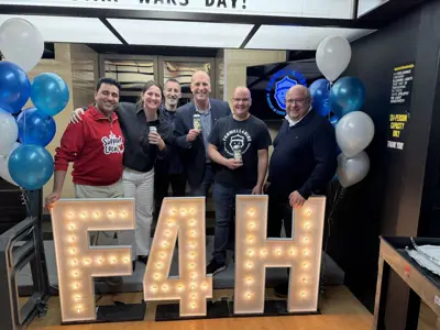 Adults posing in front of marquee letters that say F4H