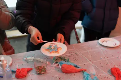 close up of people decorating sugar cookies with icing and sprinkles