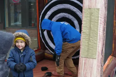 little boy standing in front of inflatable axe throwing
